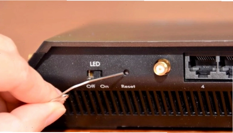 Dùng que chọt vào nút reset để khởi động lại router