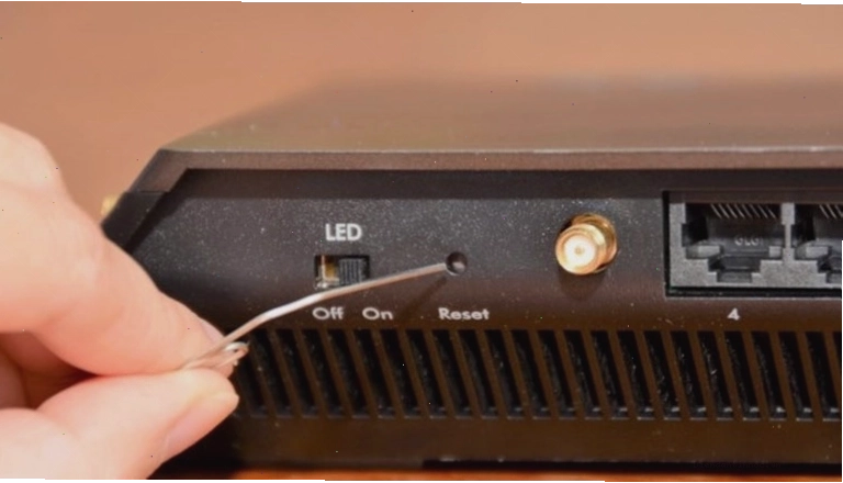 Sử dụng que chọc để nhấn nút reset trên router