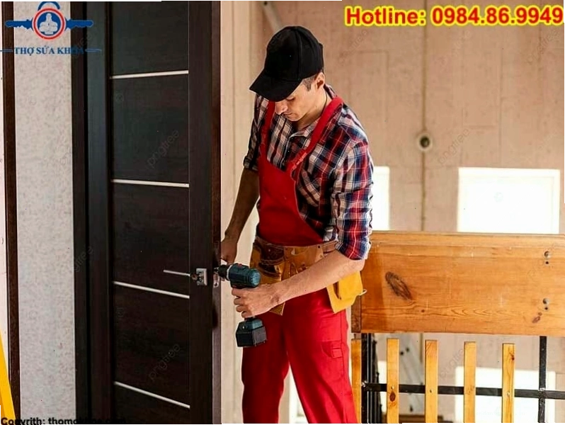 Thợ sửa khóa đang sử dụng máy khoan để thay thế ổ khóa cửa.